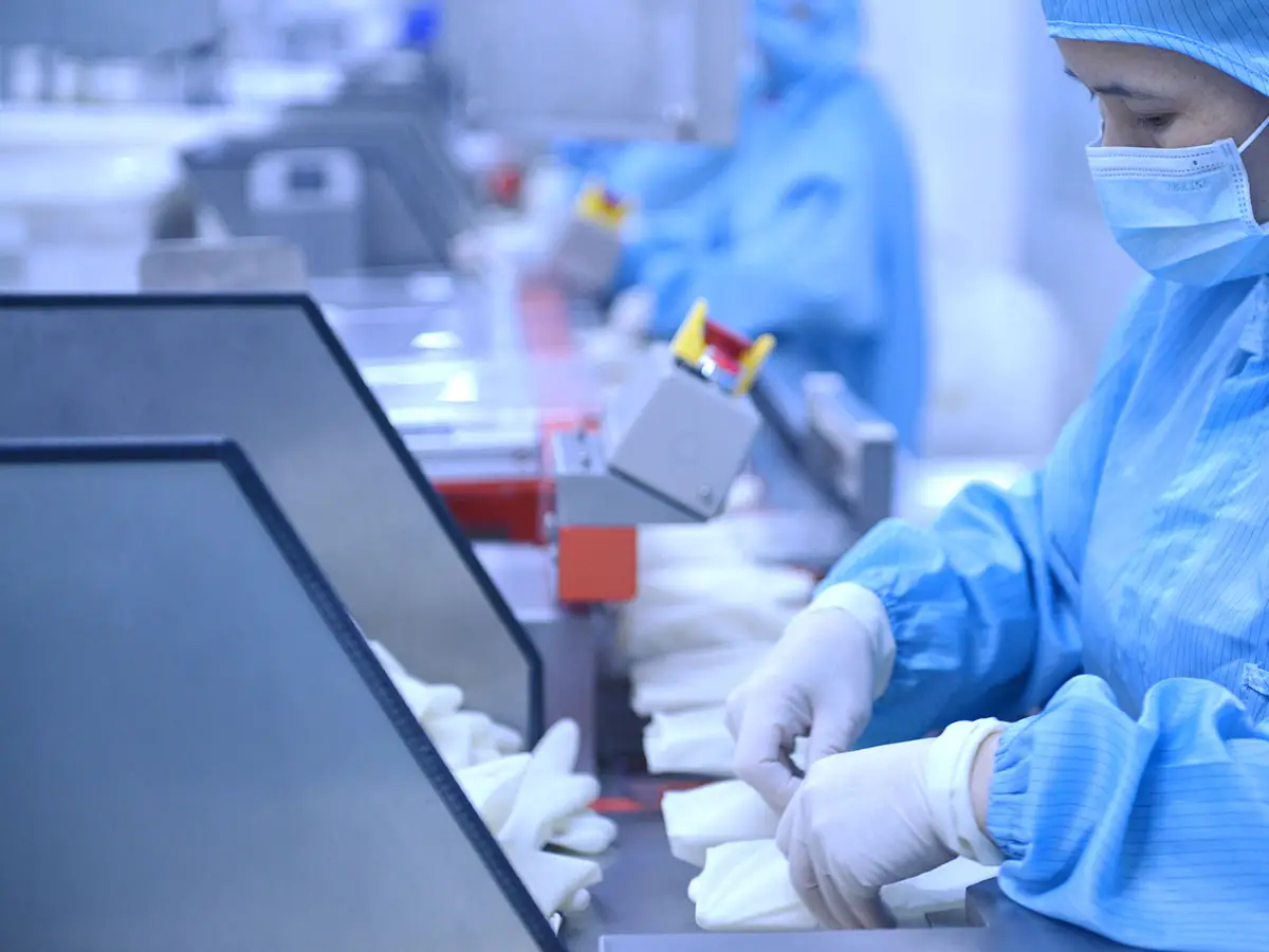 Cleanroom workers packing sterile surgical gloves on HBM production line