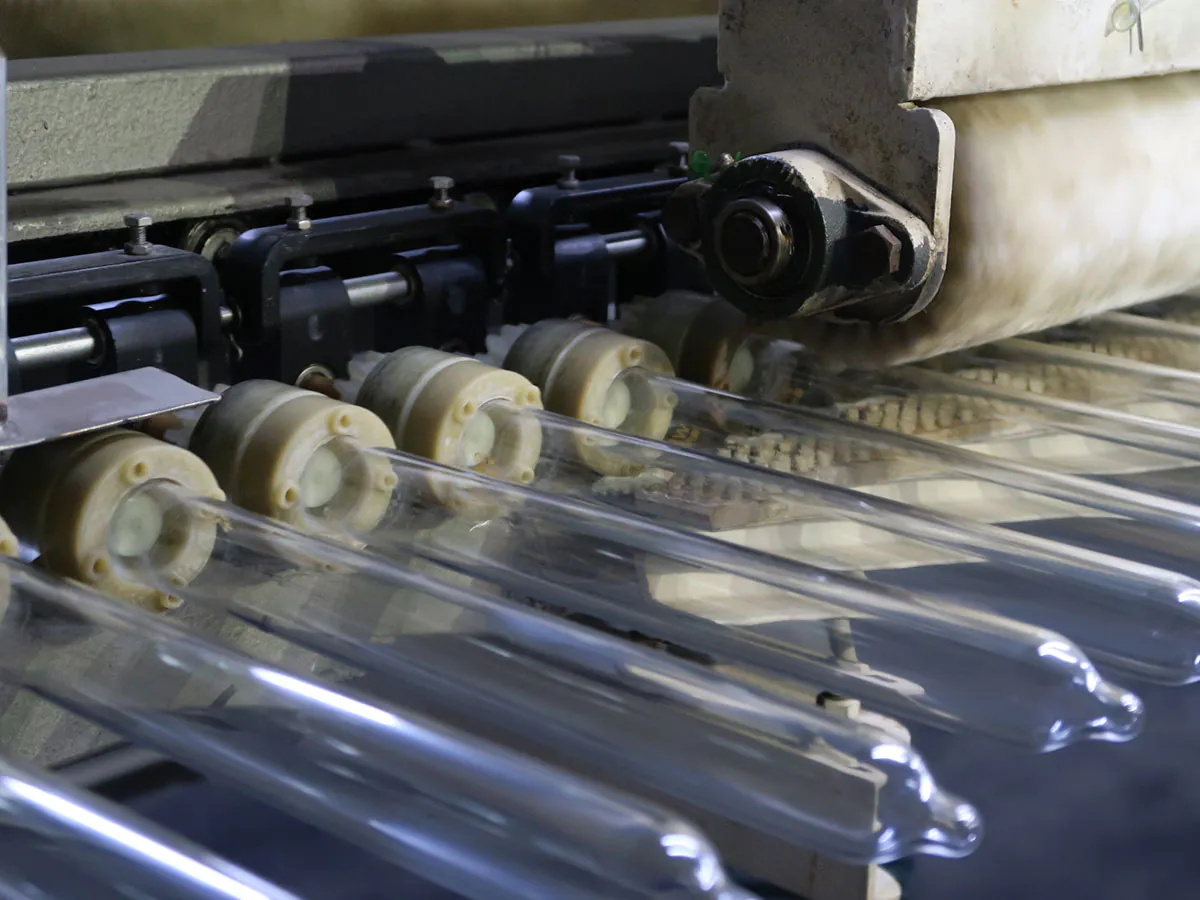 Condom rolling and stripping stage on BENOW production line, glass formers on conveyor
